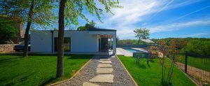 Modern single-story home with pool and landscaped gravel pathway