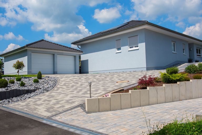 Contemporary house with paver driveway and manicured front landscaping