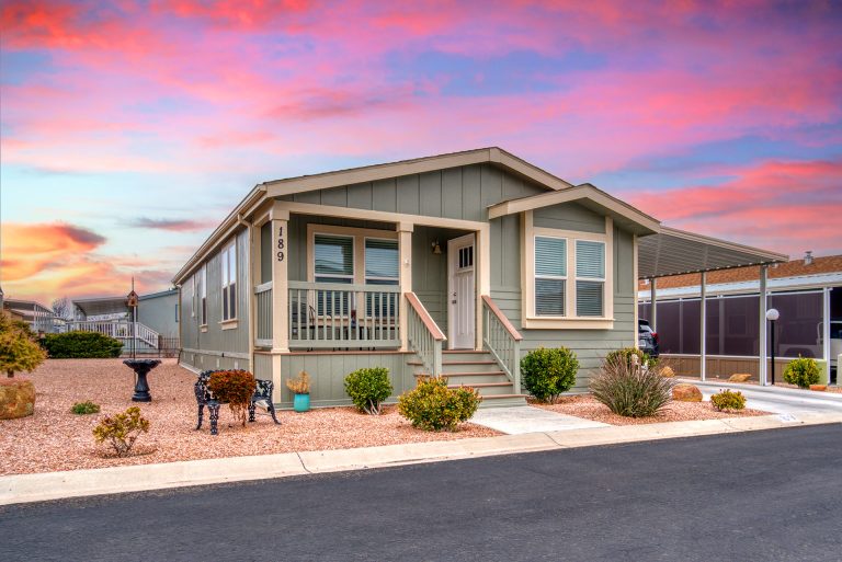 Green modular home exterior with covered porch at sunset
