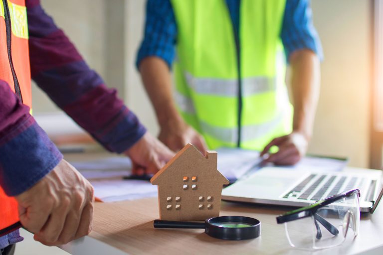 Contractor hands reviewing blueprints with house model prop