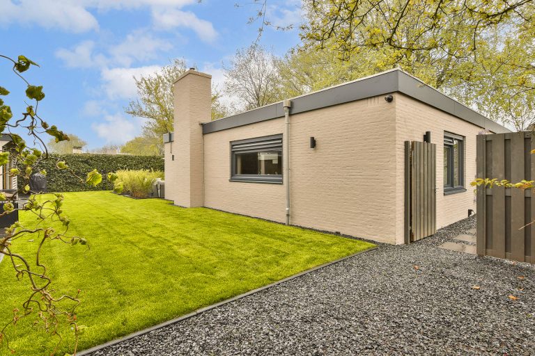 Single story modular home exterior with landscaped backyard lawn